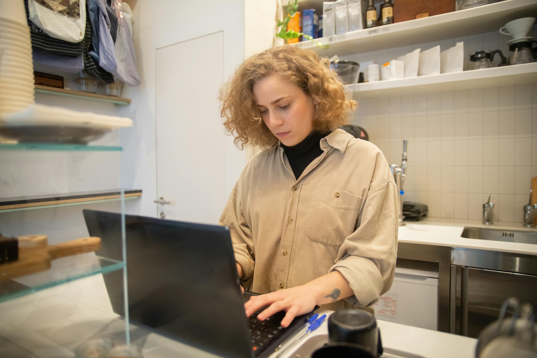 Small business owner working on a laptop behind a counter.